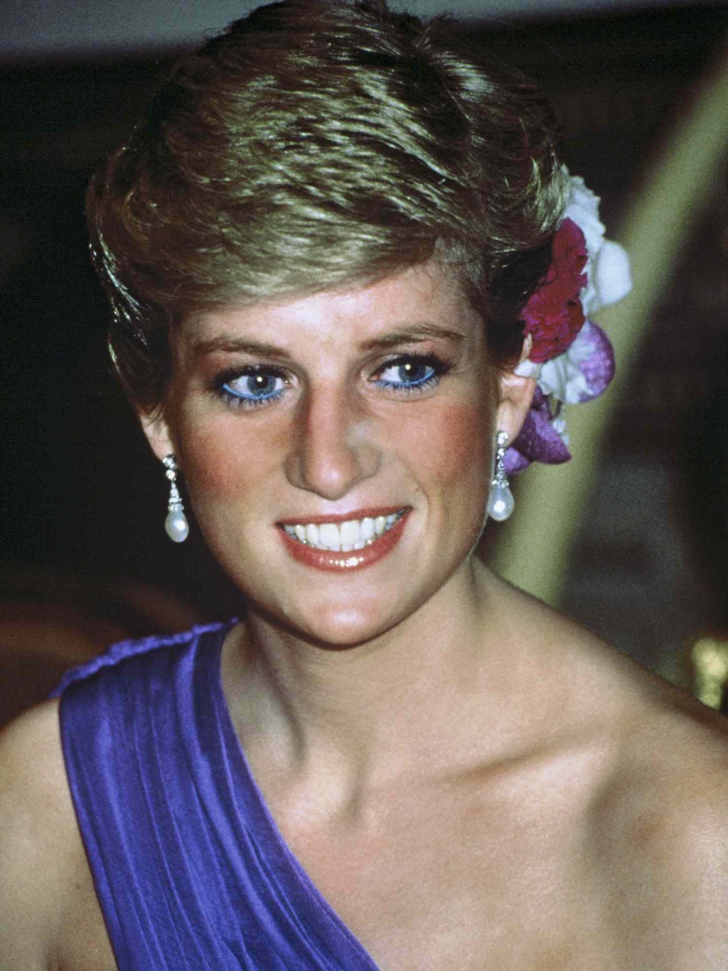 Princess Diana wears a short hairstyle with floral hair accessories, pearl earrings, and purple gown