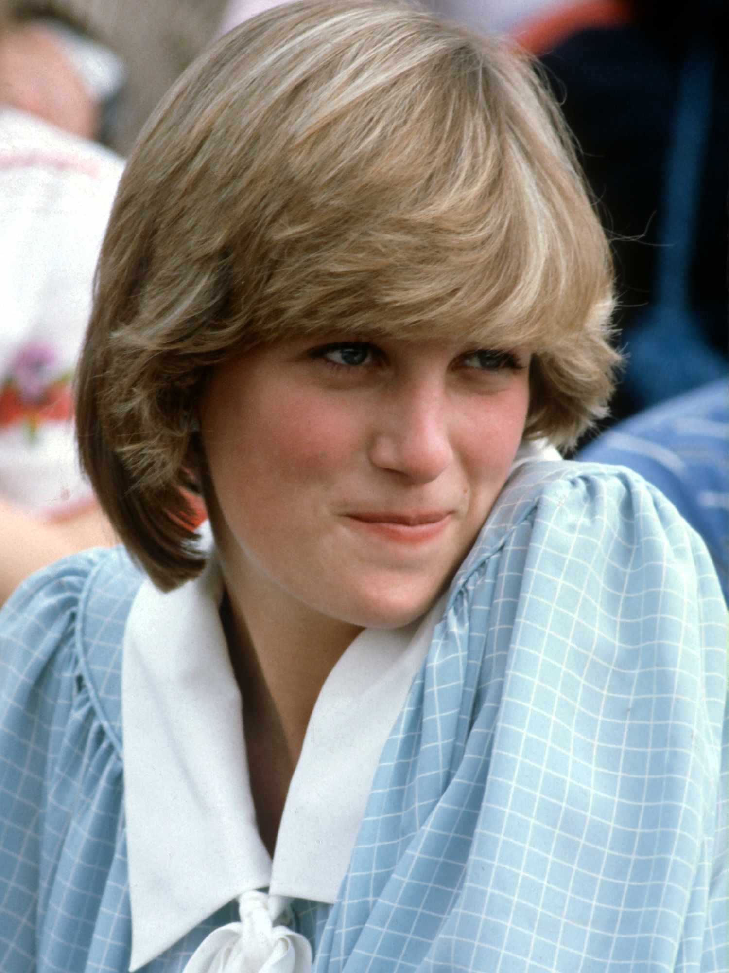 Princess Diana wears a bob haircut with bangs and a blue-green patterned dress with a white collar
