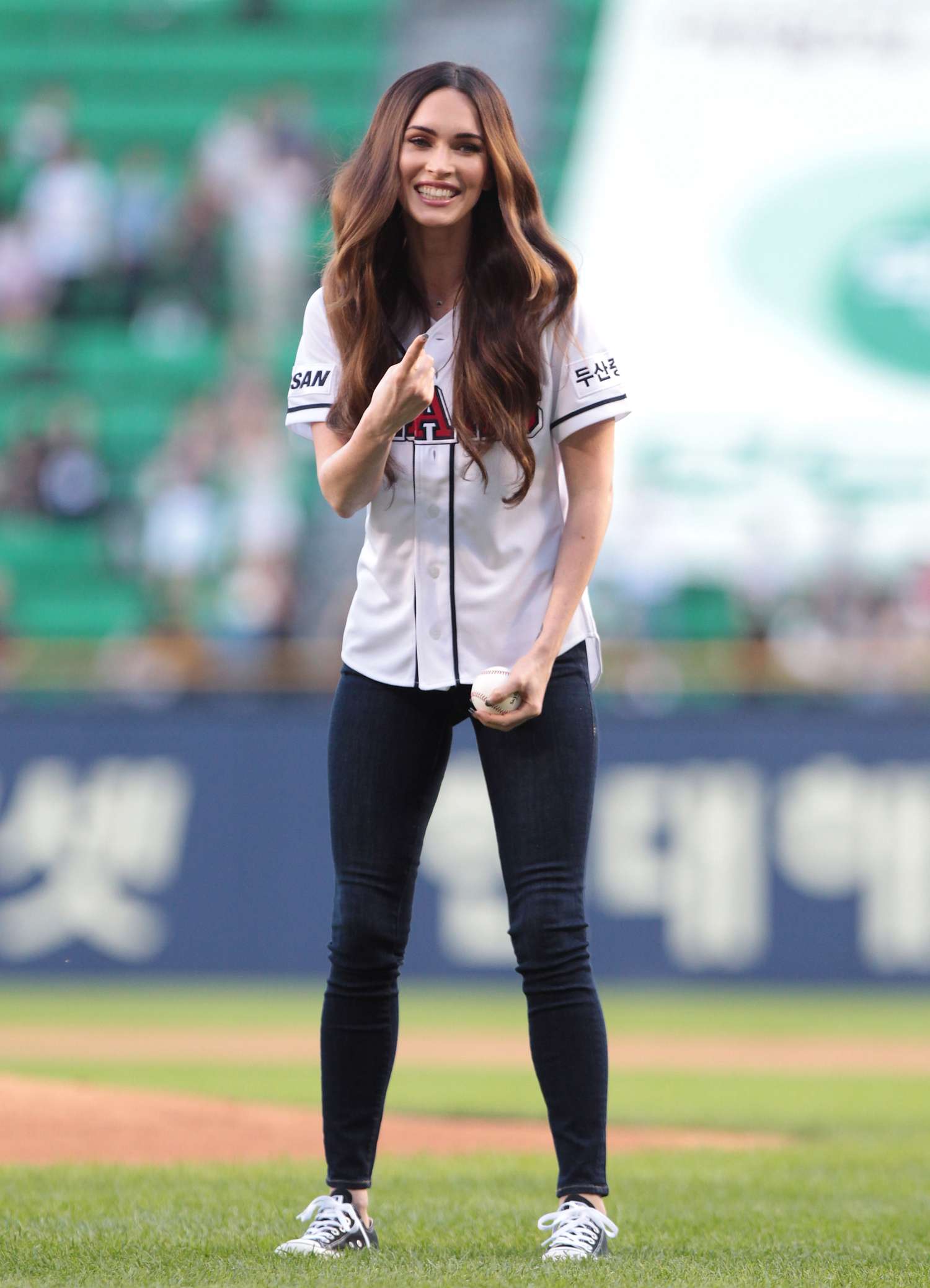 Megan Fox in Seoul, South Korea, throwing the first pitch at the LG Twins vs. Doosan Bears baseball game with voluminous wavy wooden hair