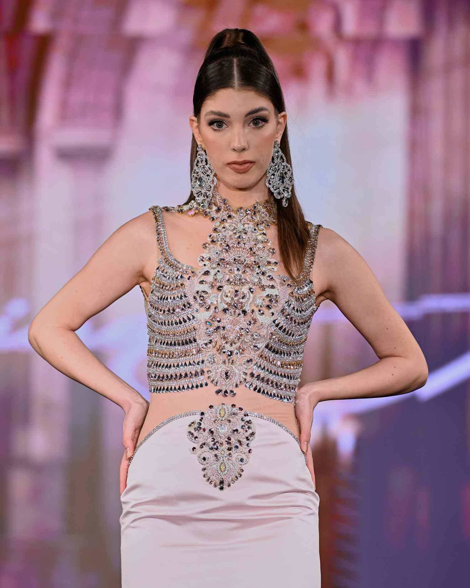 A model walks the Giannina Azar ruway show wearing a sleek high pony and beaded gown. 