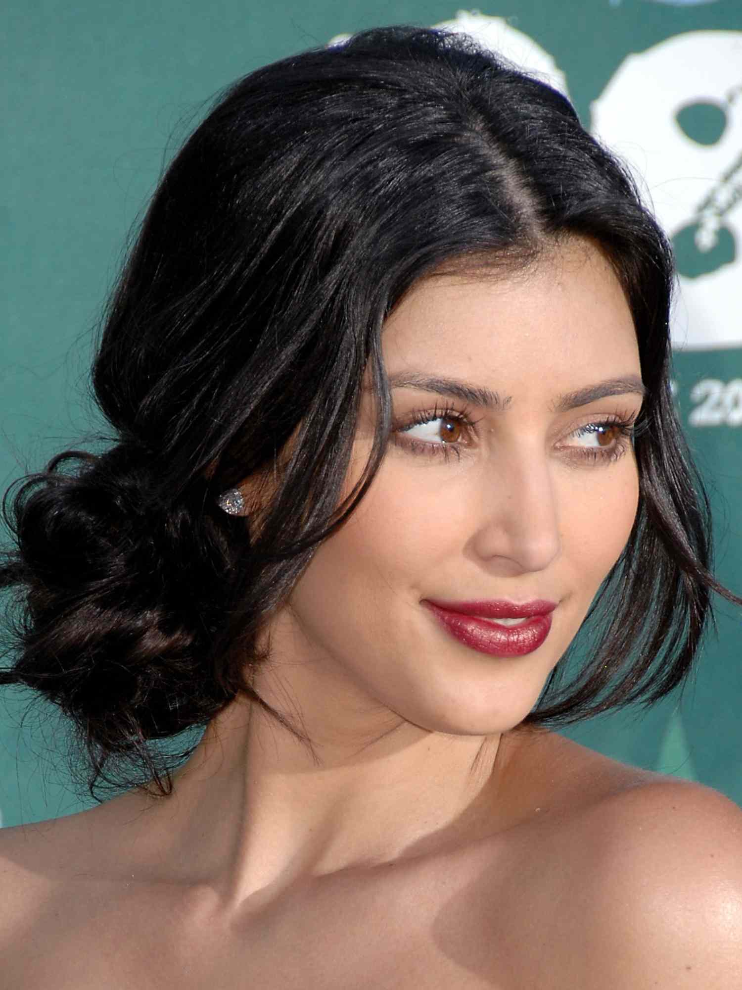 Kim Kardashian with loose chignon hairstyle, deep red lipstick, and minimal mascara