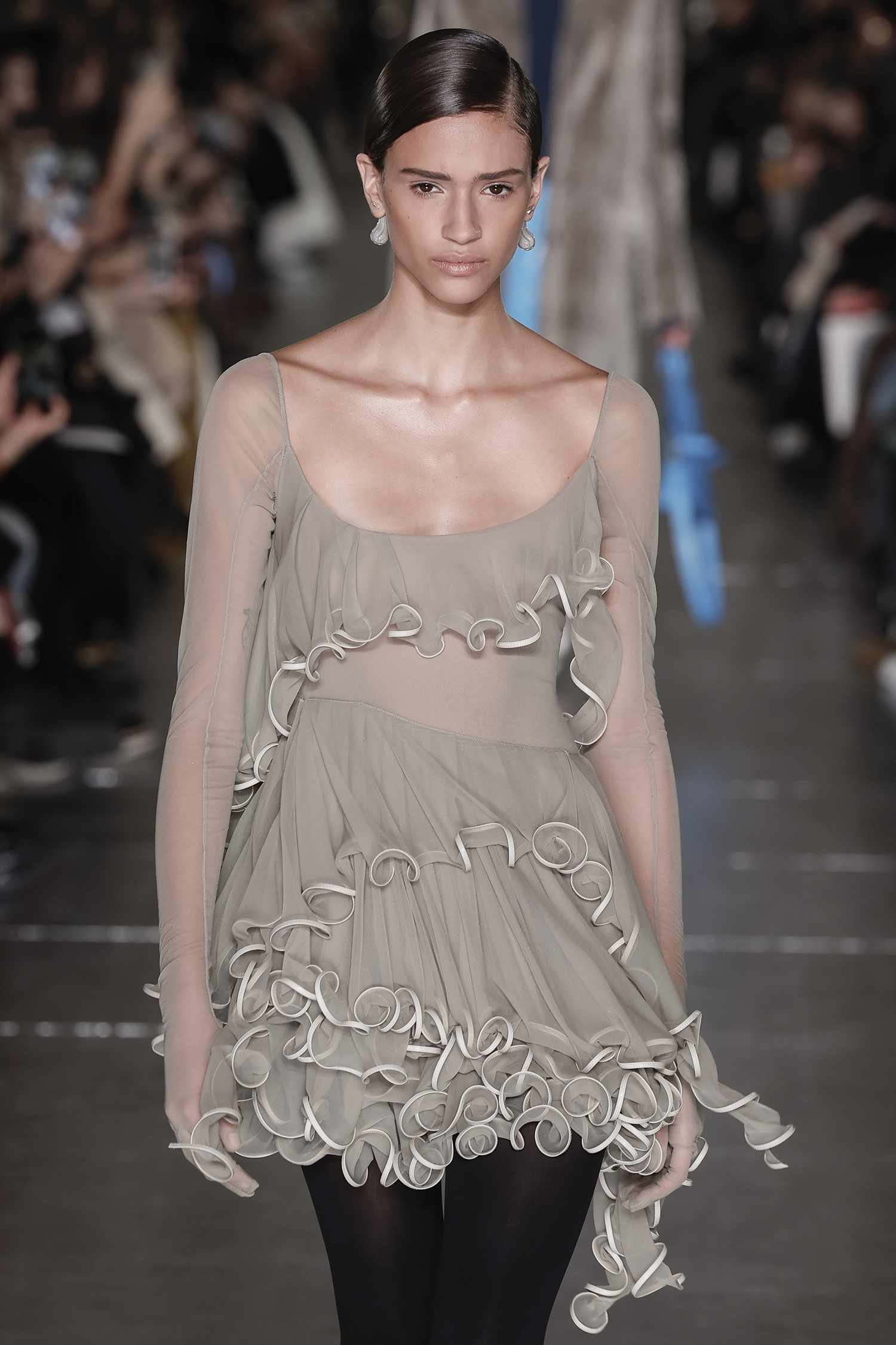 A model walks the Tory Burch runway wearing a mini dress with ruffles. 