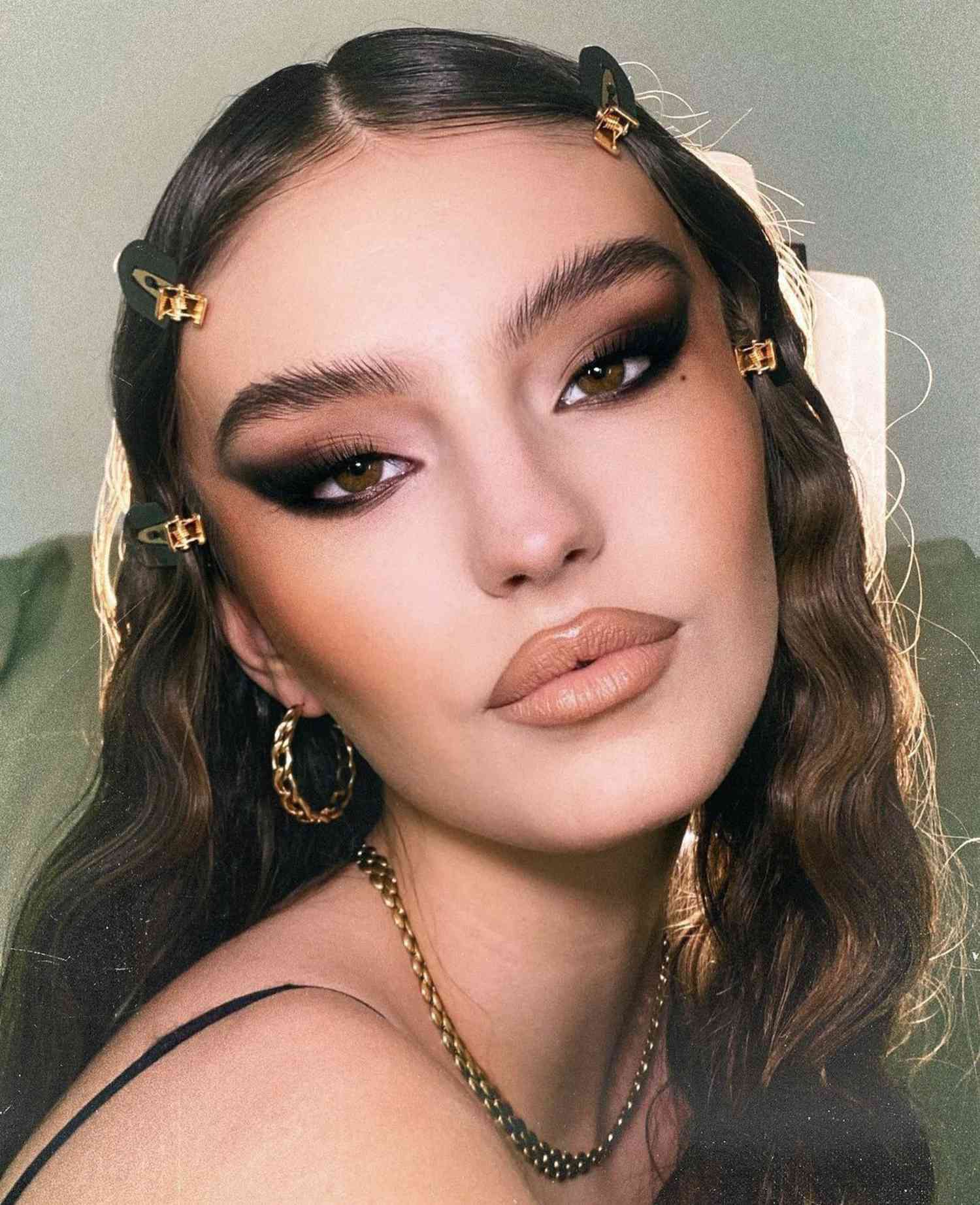 woman wearing smoky eyeshadow in a graphic wing liner shape with matte nude light tan lipstick and defined brows and cheekbones