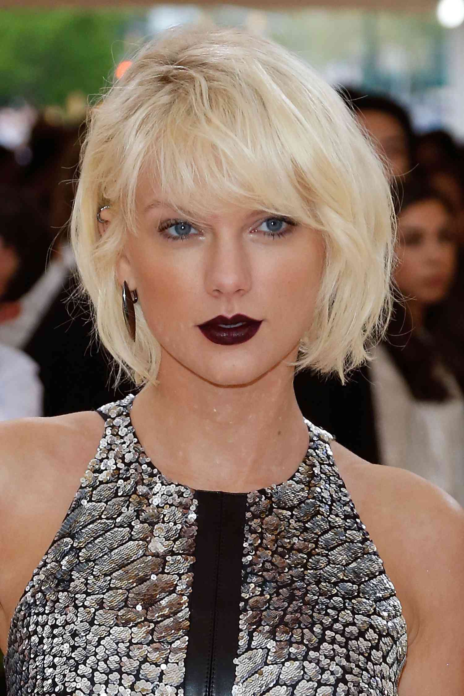 Taylor Swift wears dark crimson lipstick and white iridescent eyeshadow