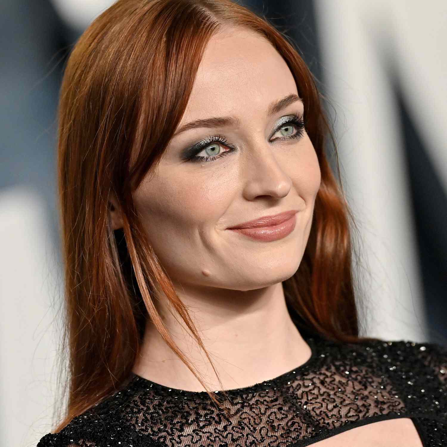 Sophie Turner with red hair and layered bangs on the Vanity Fair Oscar party red carpet