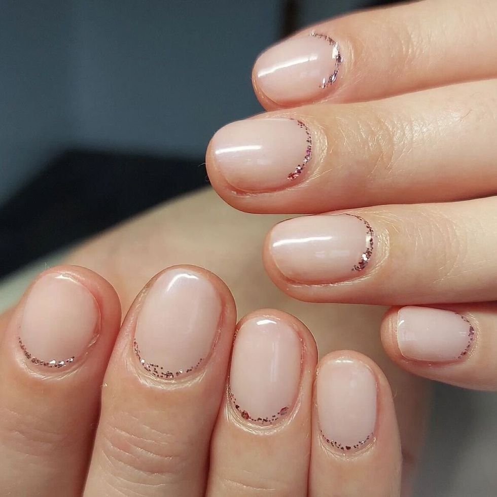 a close up of a hand with painted fingernails and glitter cuticles