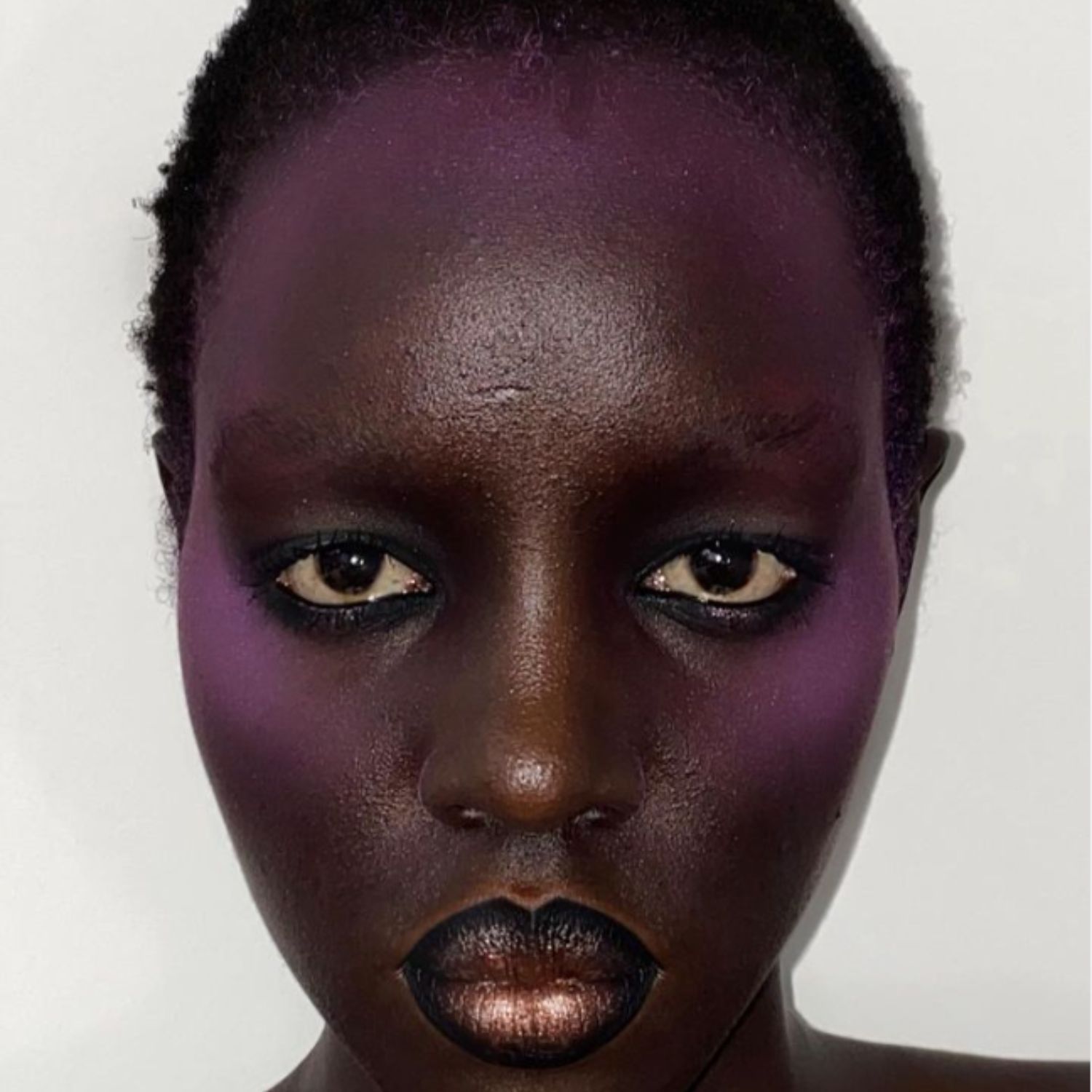 Halo blush in deep violet with black-rimmed lips that fade into a frosted bronze.