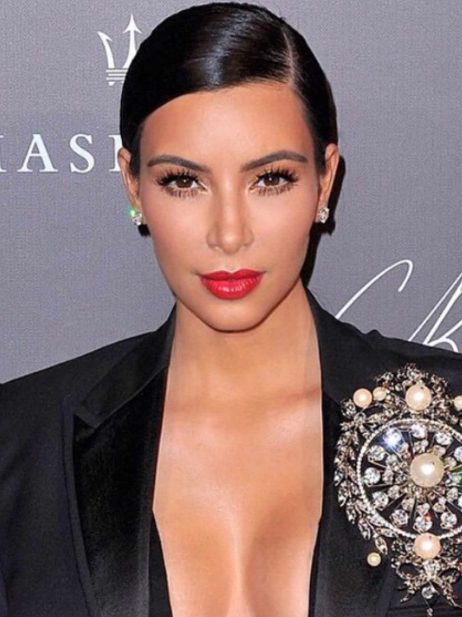 Kim Kardashian with slicked-back hairstyle, mascara, and bright red lipstick