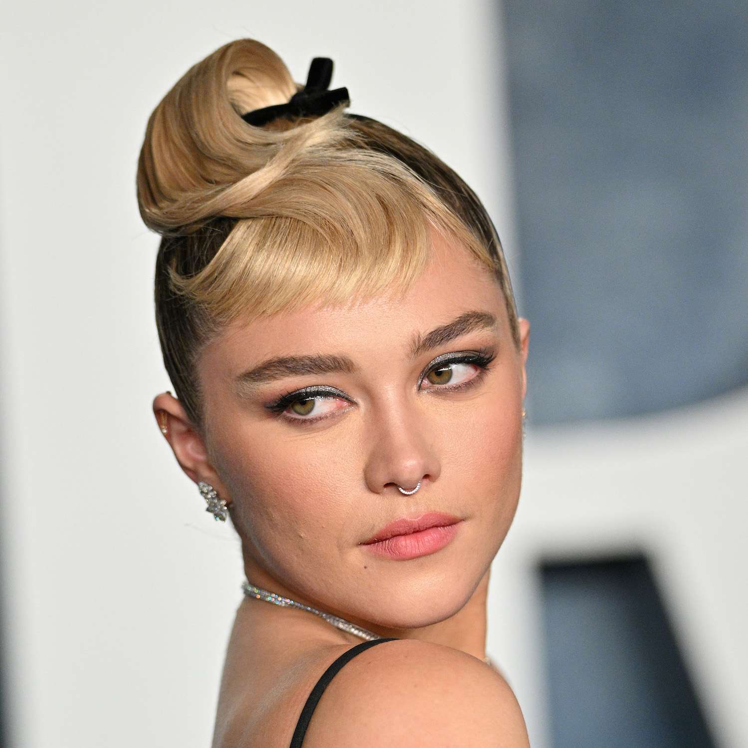 Florence Pugh wears a forward twisted updo with a black ribbon to the 2023 Vanity Fair Oscars afterparty