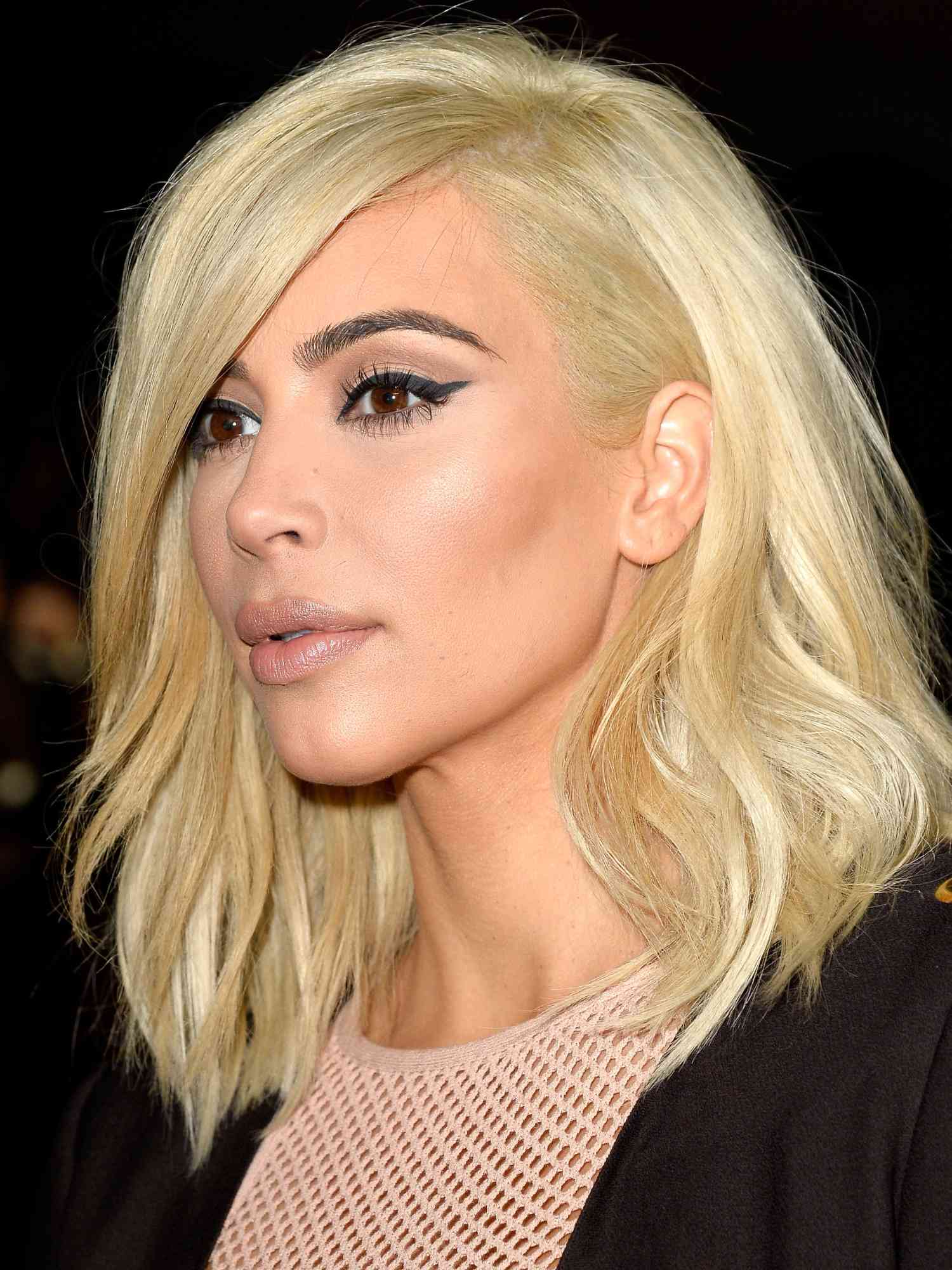 Kim Kardashian with a platinum long bob hairstyle with side part, thick black winged eyeliner, mascara, bronzed cheeks, and a nude lip