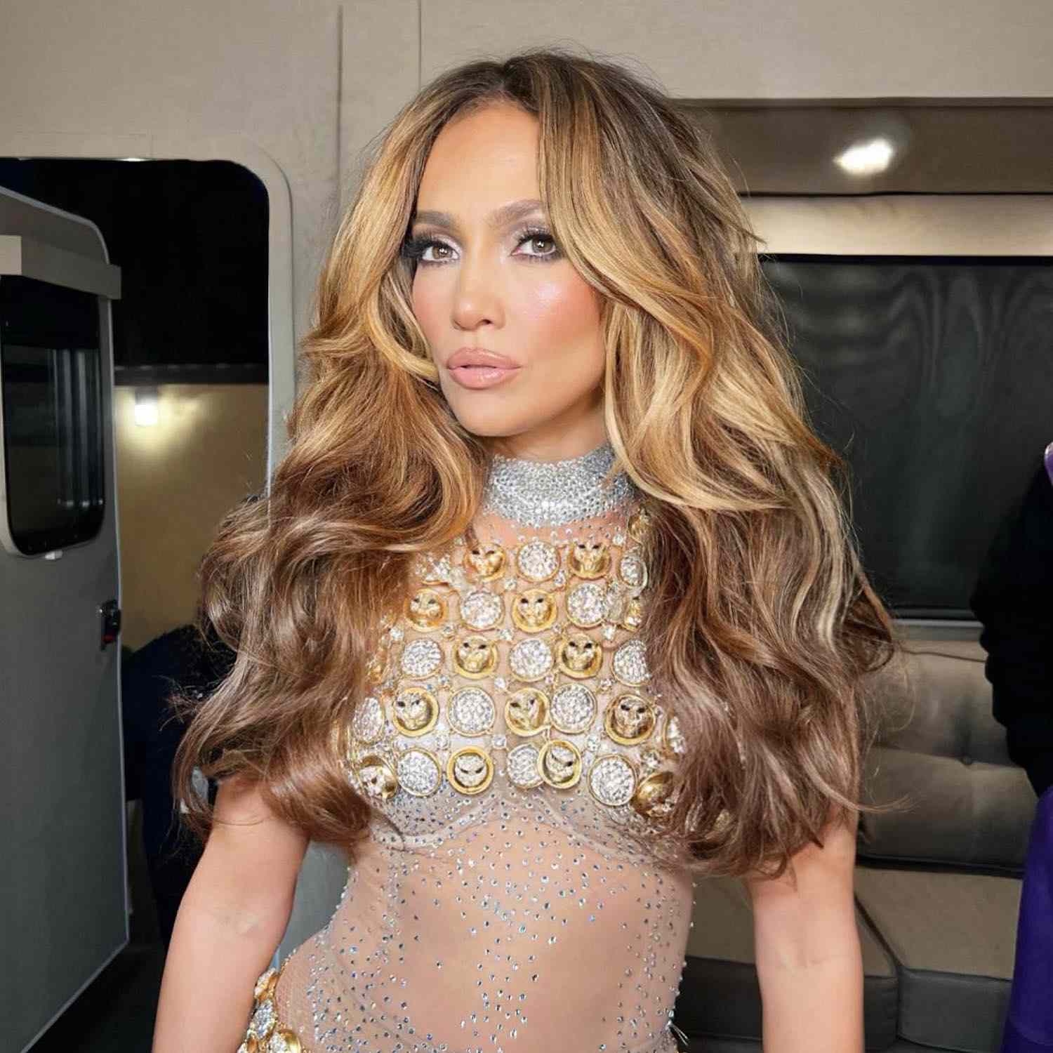 Jennifer Lopez wears a voluminous highlighted wavy hairstyle with ghost layers