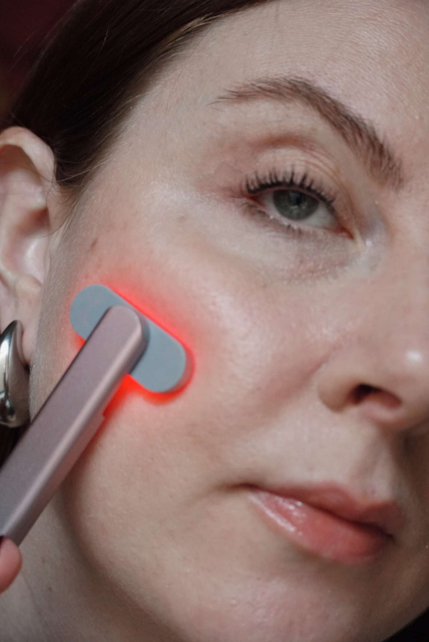 model is posing with a red light solawave wand on face