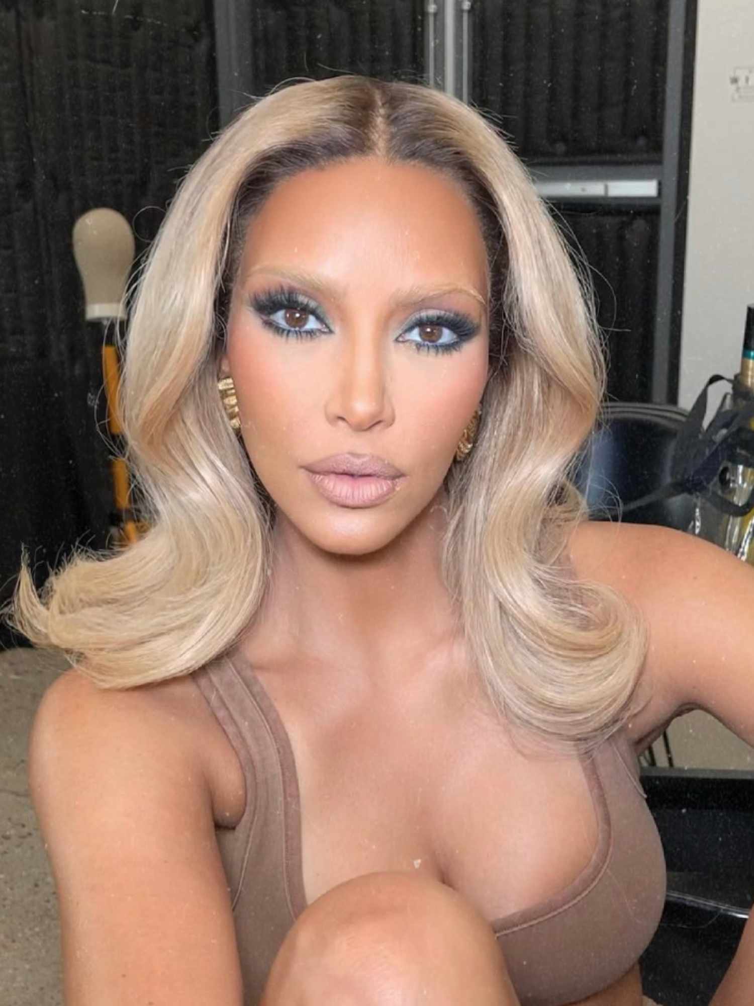 Kim Kardashian with blonde bouncy blowout, bleached blonde brows, dark eye look, and nude lipstick