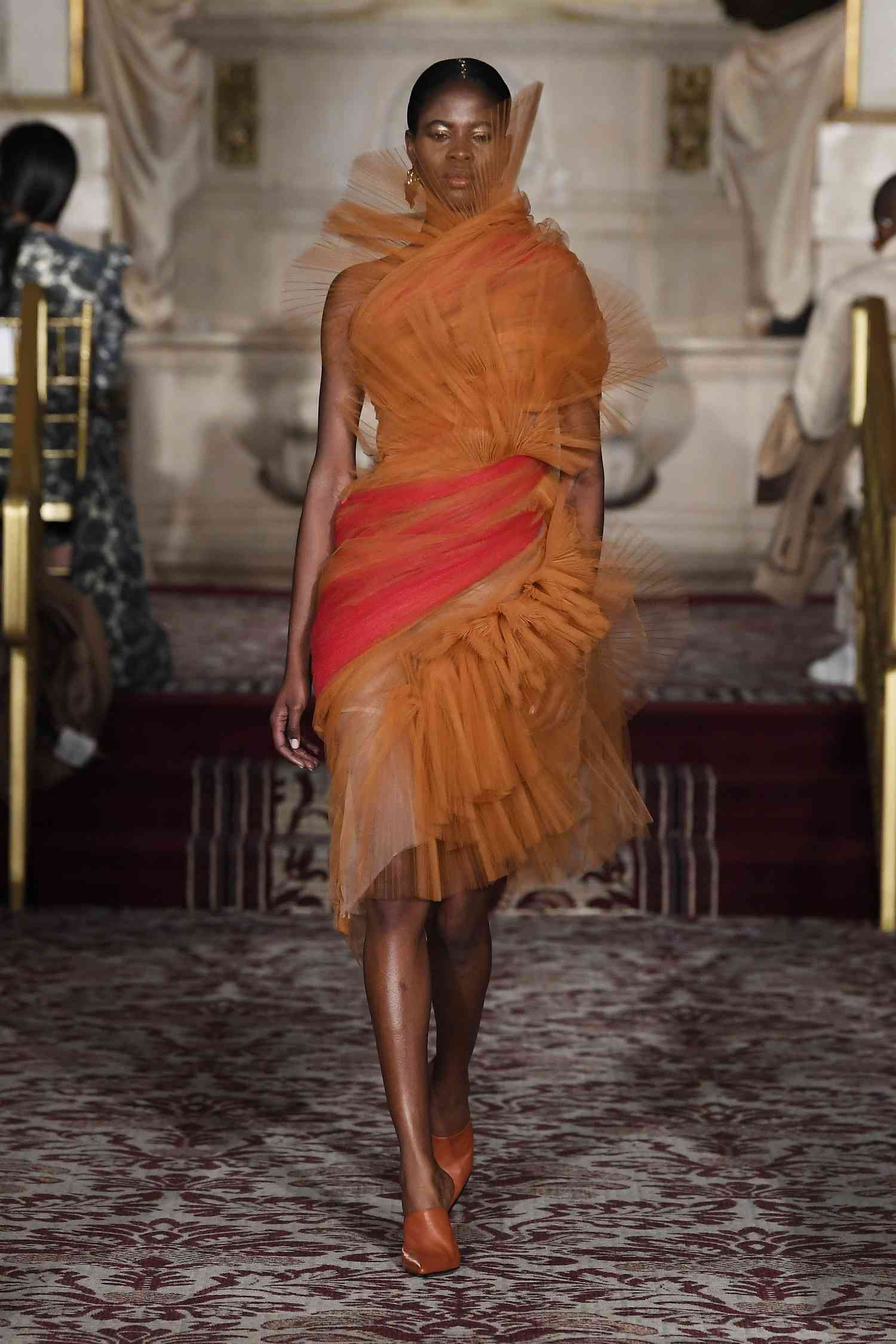 A model on the runway at the Christian Siriano show wearing an organge tulle dress.