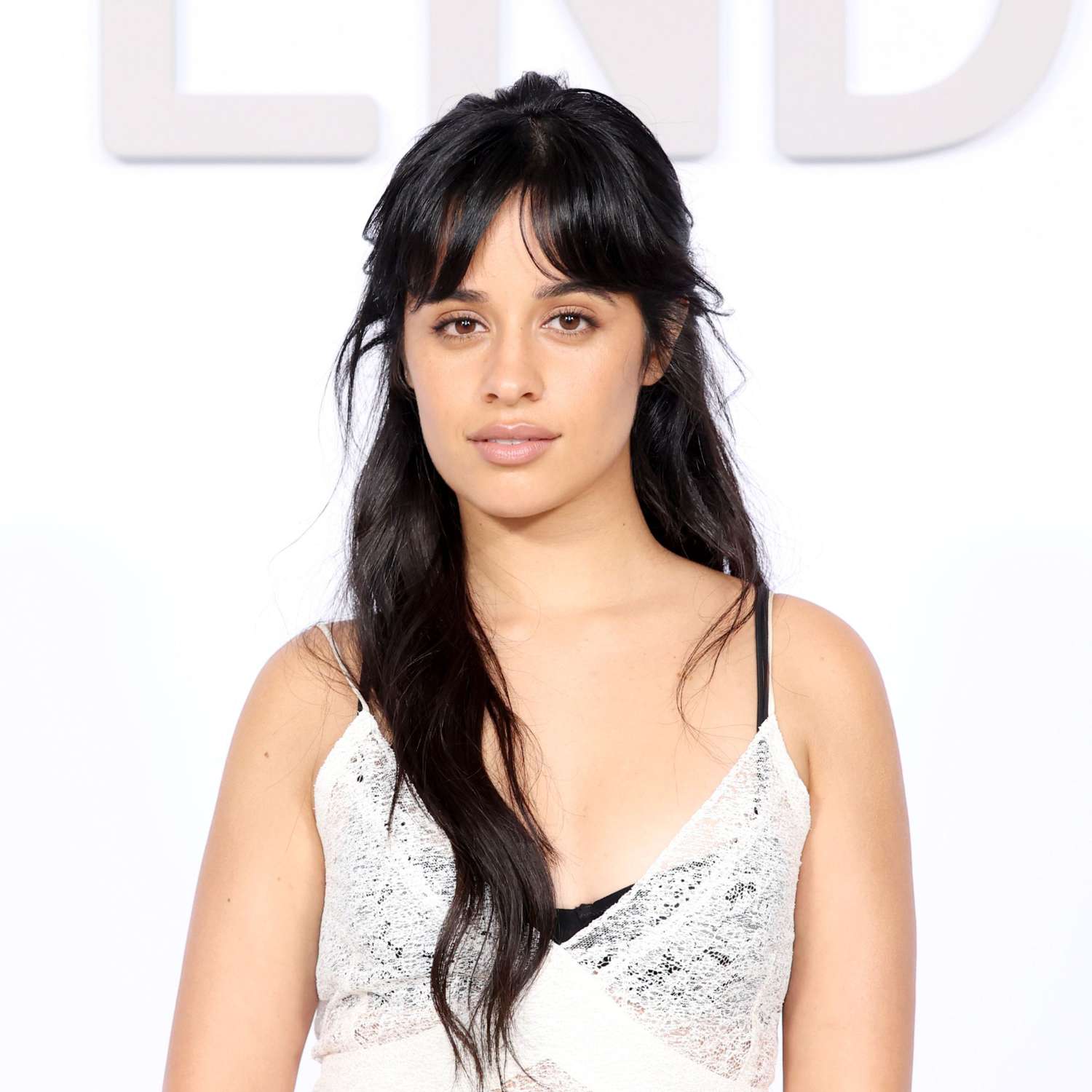 Camila Cabello with long hair in a half-up hairstyle with long, face-framing bangs