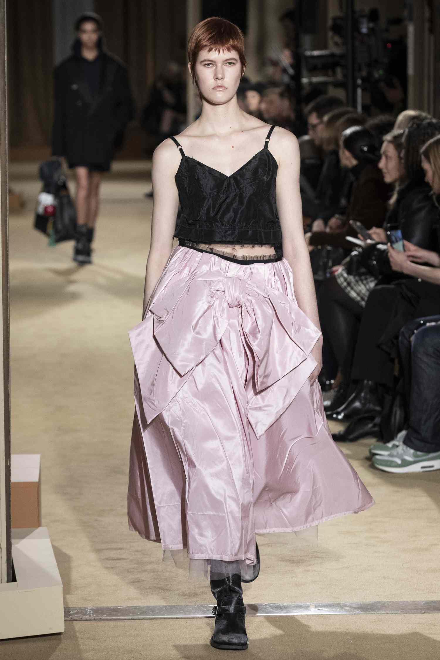 Model wearing a black tank and pink bow skirt at the Coach runway show. 