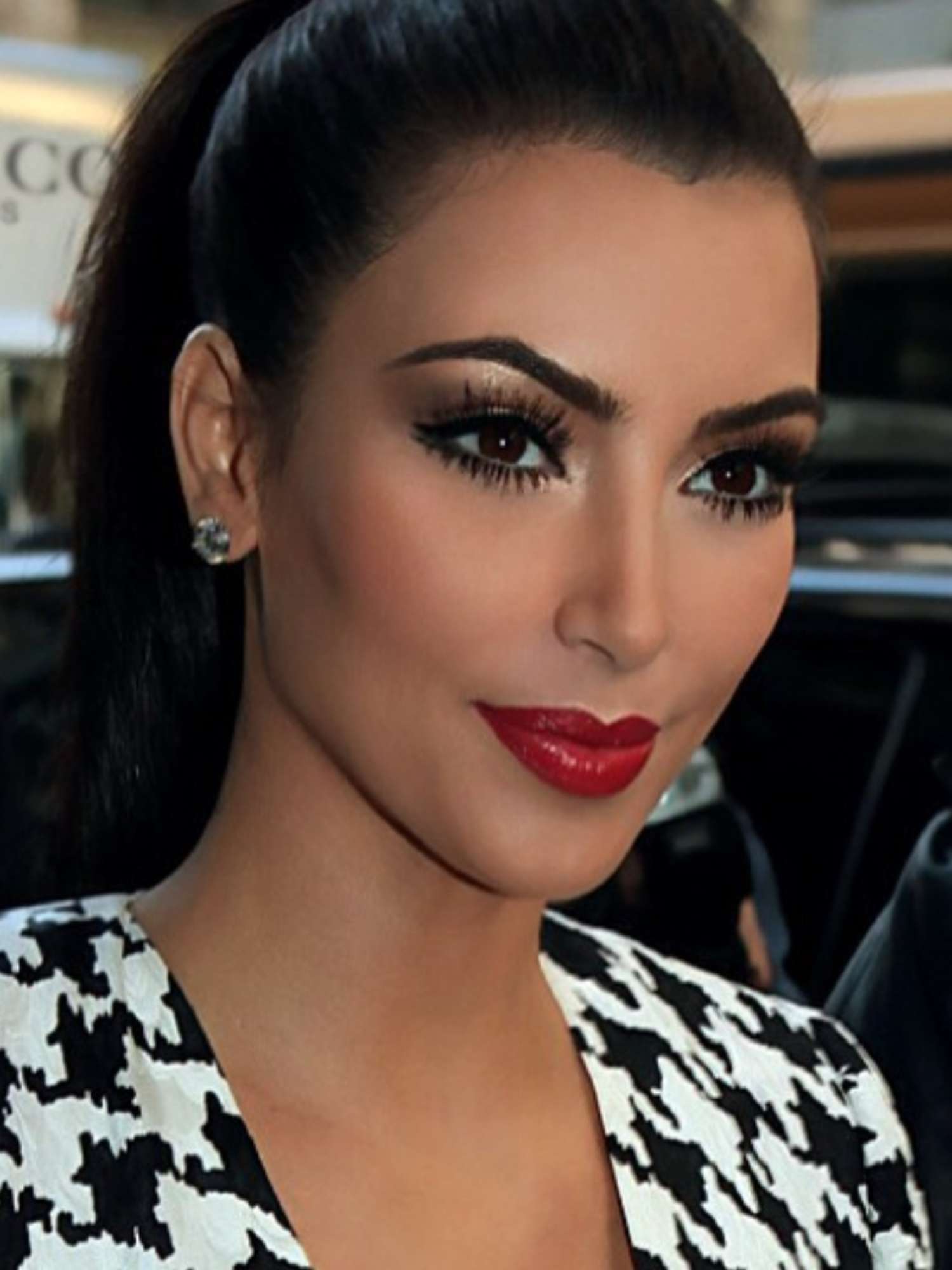 Kim Kardashian with long black spider lashes, shimmer eyeshadow, and red lipstick