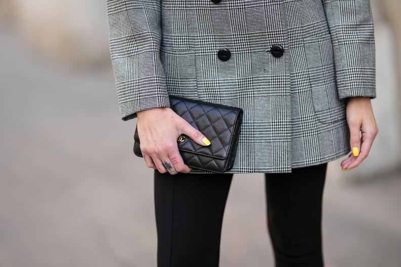 PARIS, FRANCE - MARCH 19: Emy Venturini wears a black and white small houndtooth print pattern blazer jacket from YSL / Saint Laurent Paris, black legging pants, a black shiny grained leather clutch from Chanel, during a street style fashion photo session