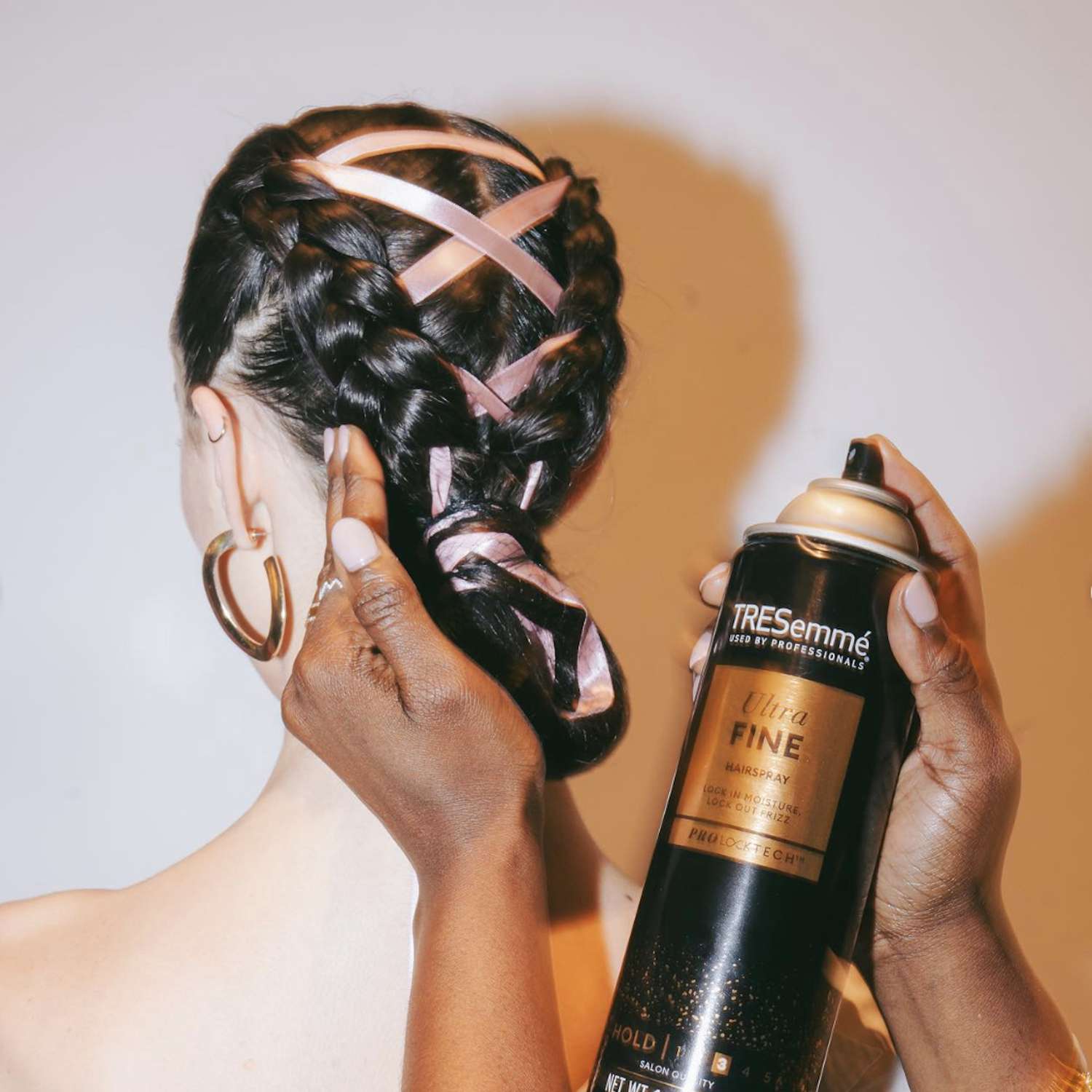 Back view of model with braided low updo hairstyle with corseted ribbons