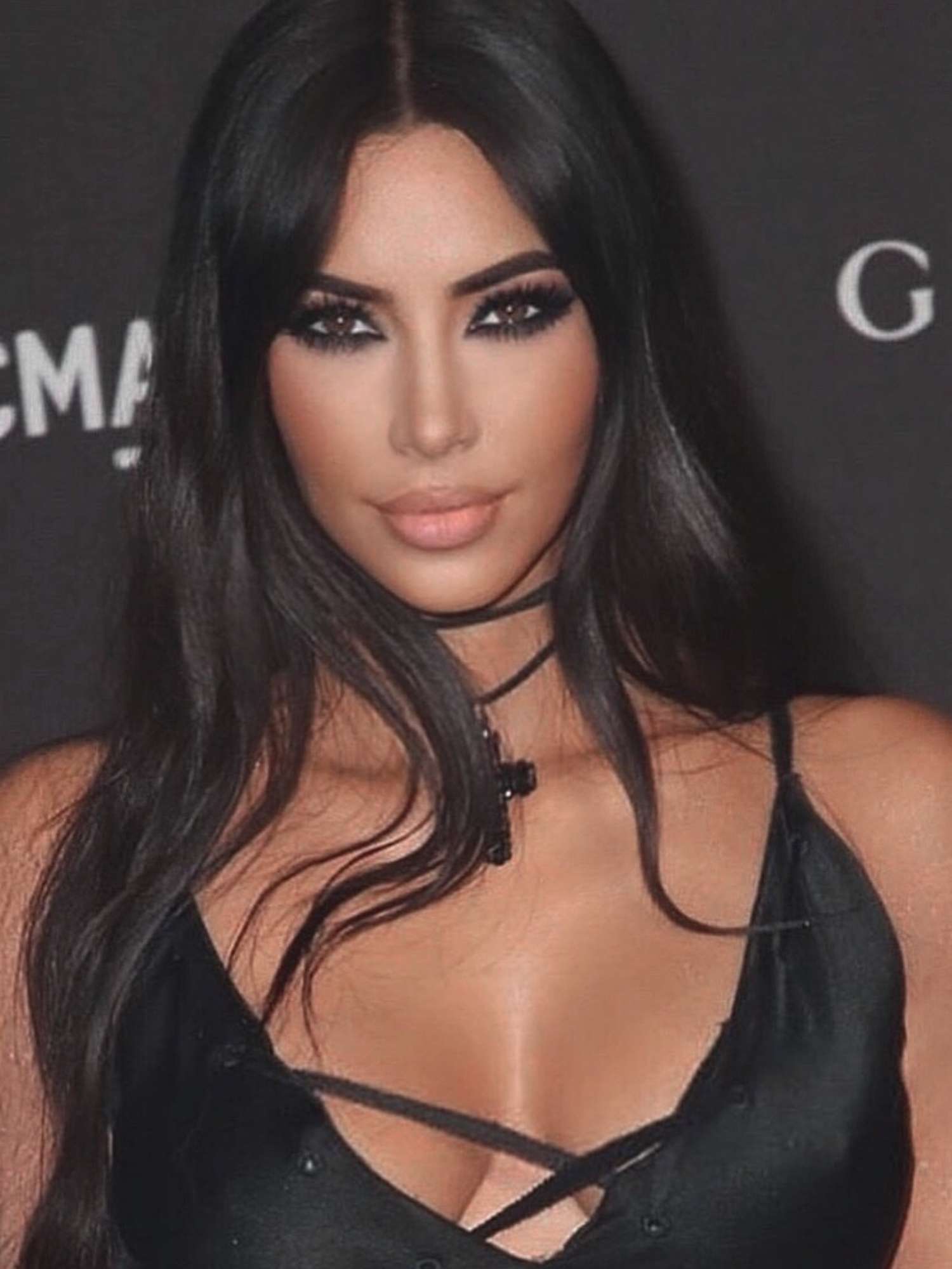 Kim Kardashian with long, jet-black hair, a black smoky eye, and nude lipstick