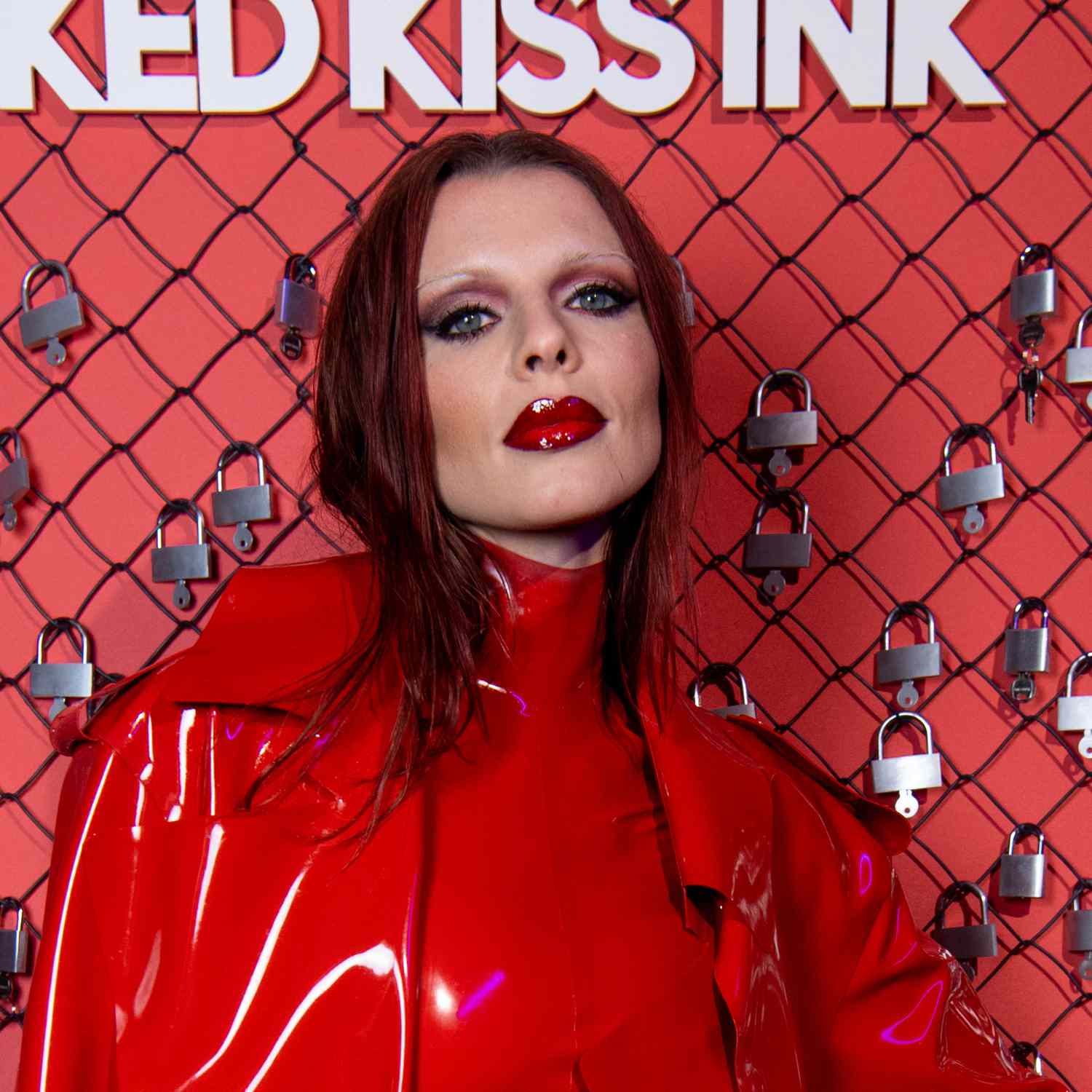 Julia Fox wears red smoky eyeshadow with intense black liner around the entire eye, and patent leather red lips with thin eyebrows