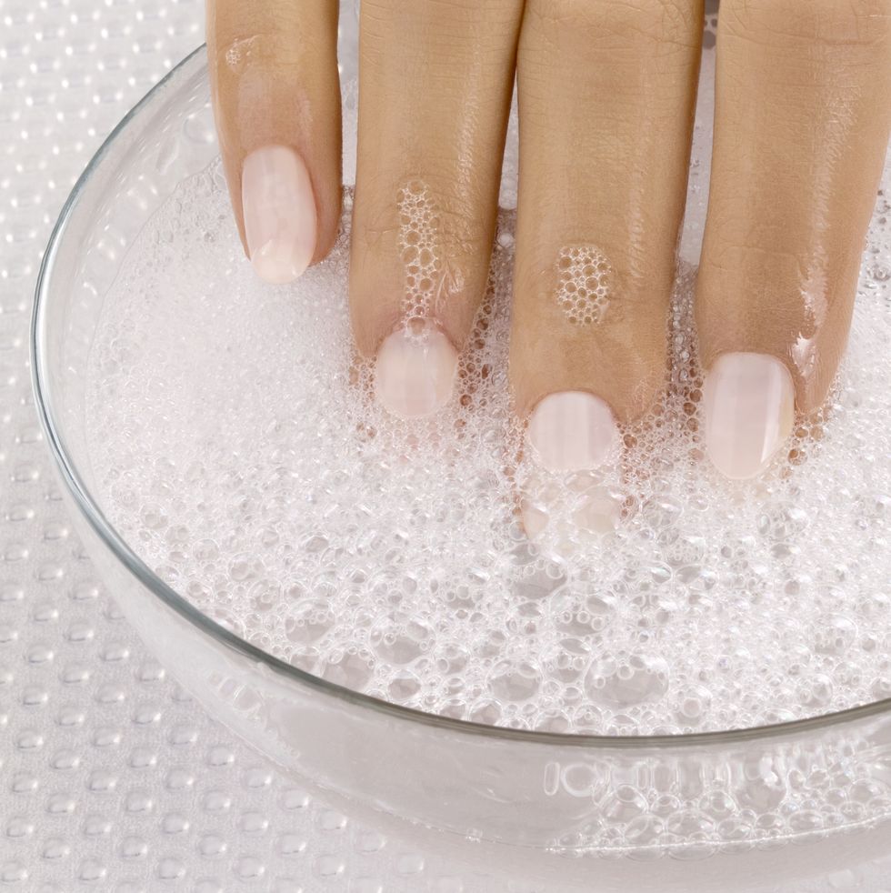 Close up of woman's hand in bowl of soapy water