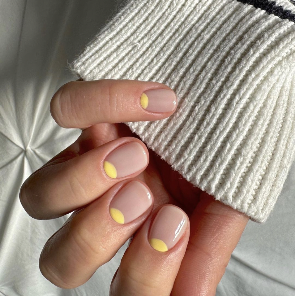 a person's hand with painted nails with yellow half moons