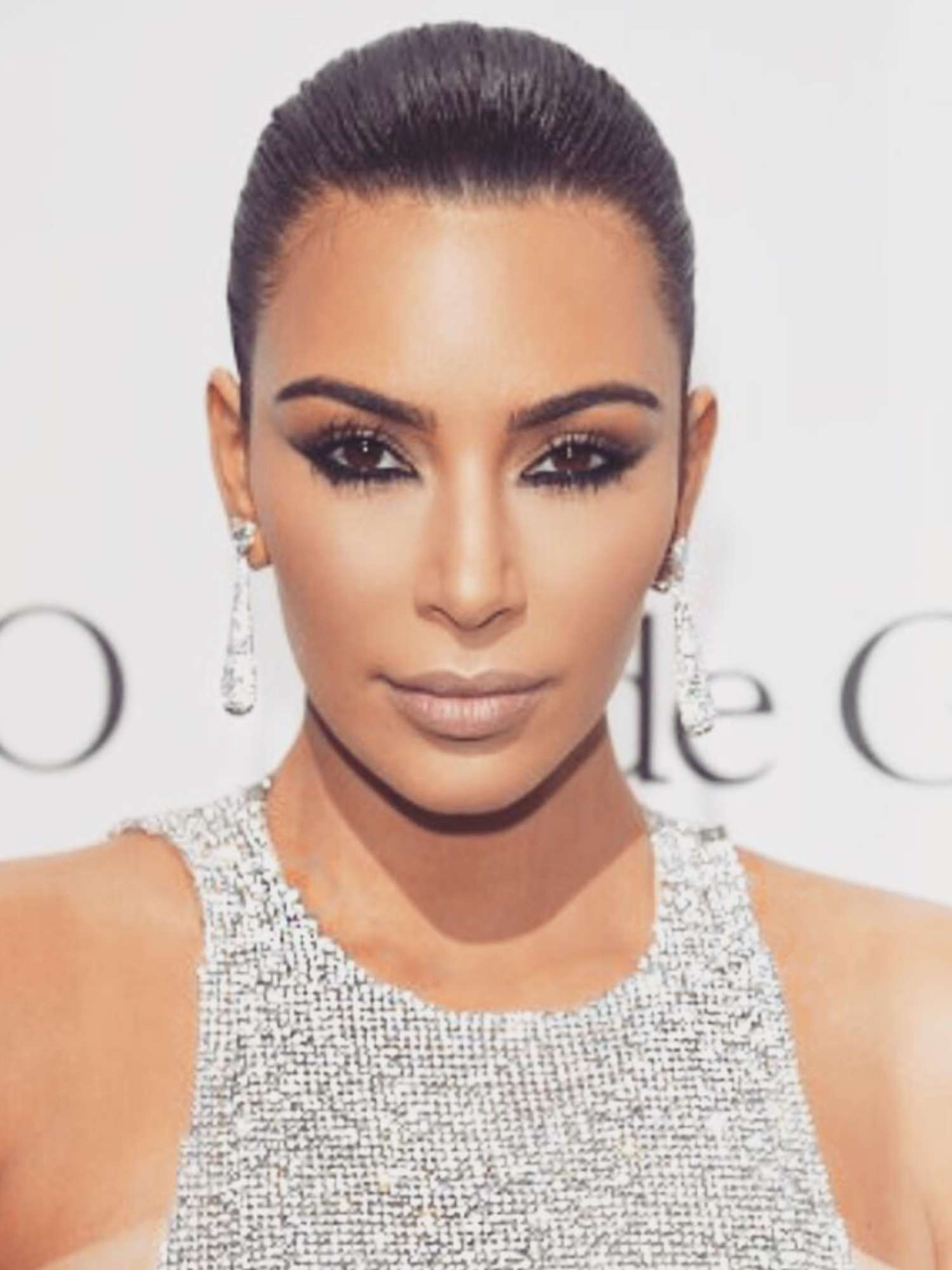 Kim Kardashian with slicked-back hairstyle, nude lipstick, and smudged black eyeliner