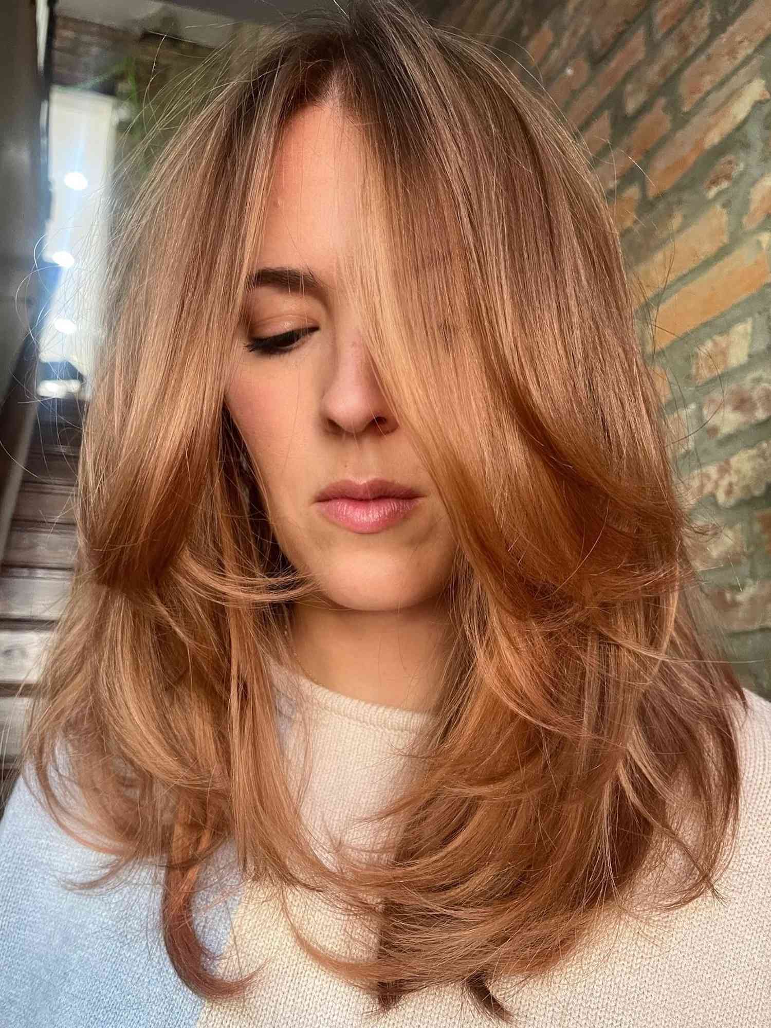 Woman with shiny layered ginger hair with subtle blonde highlights