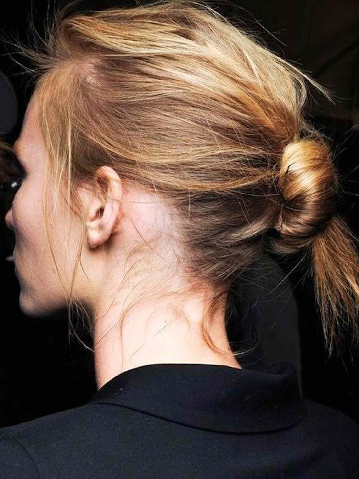 Back view of woman with blonde and ginger hair in tousled center bun hairstyle