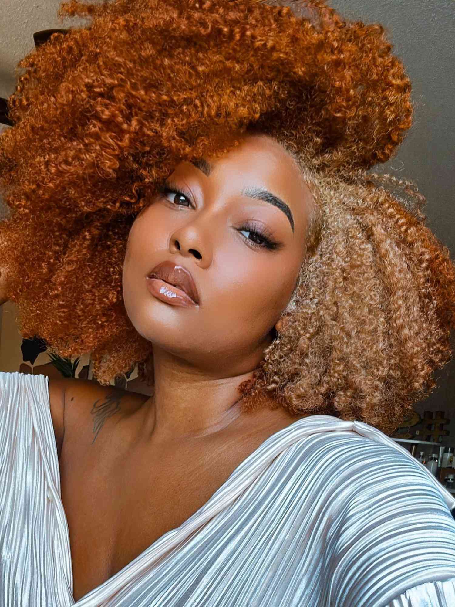 Woman with red and blonde naturally curly hair and radiant glam makeup