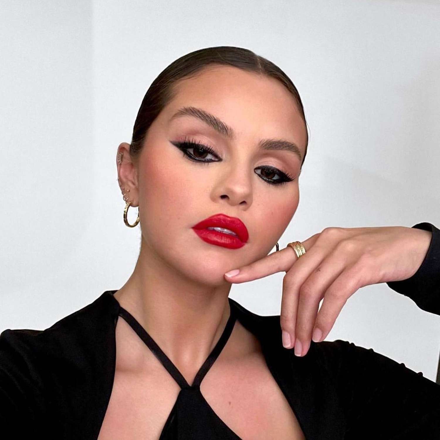 Selena Gomez wears a slicked back bun with a red lip and cat-eye makeup