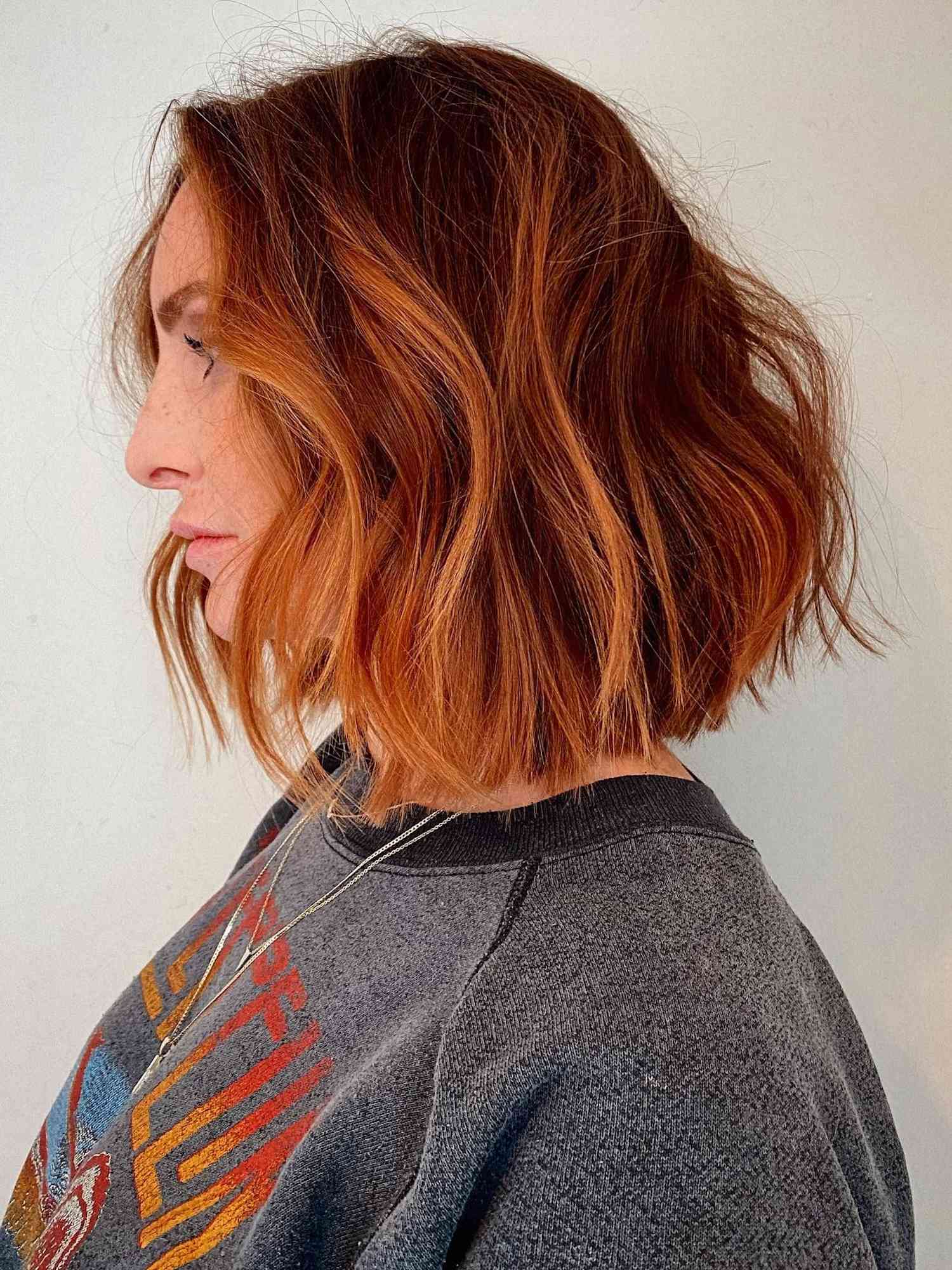 Side profile of woman with copper and ginger red balayage bob hairstyle
