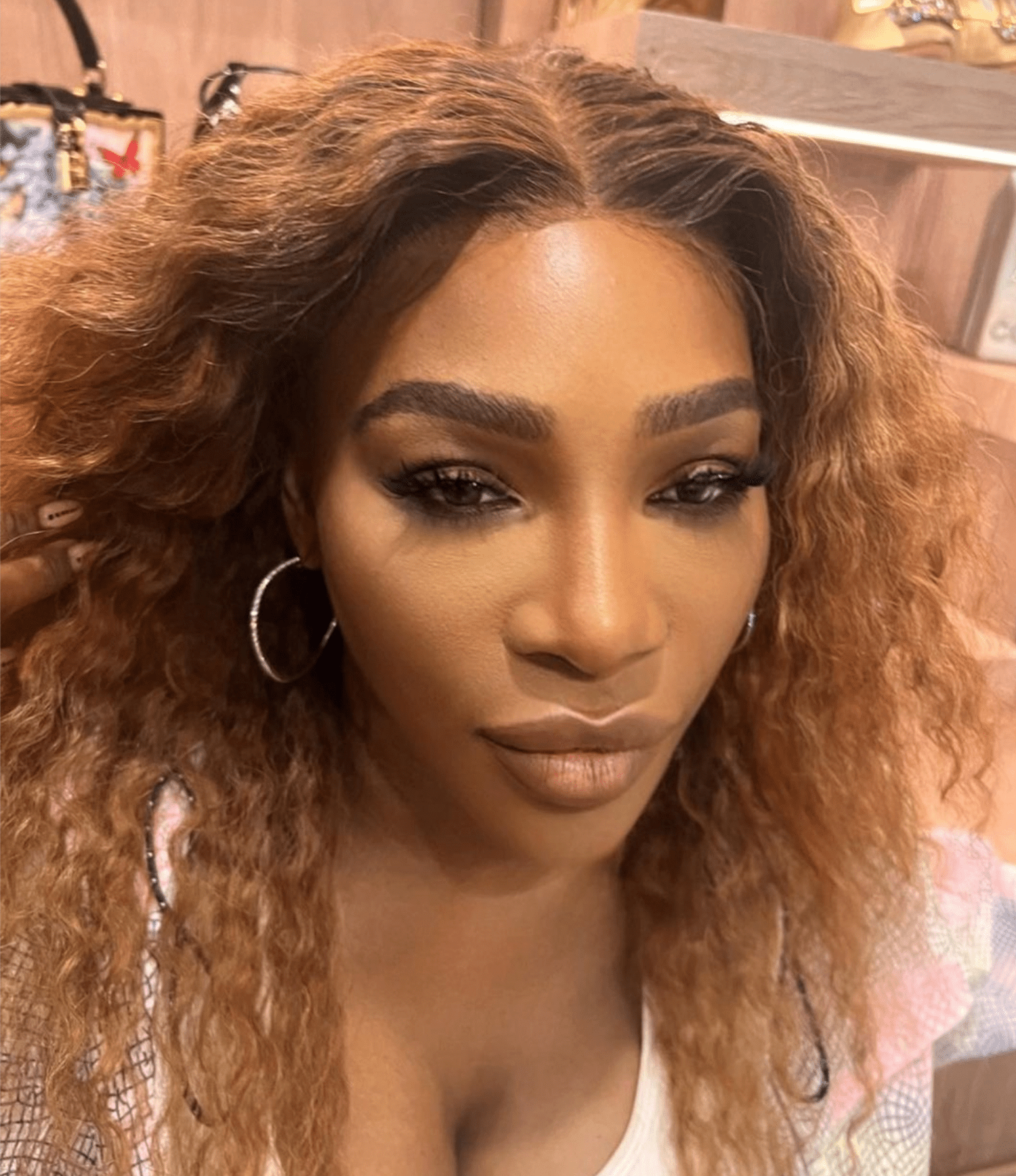 Serena Williams with naturally curly hair with copper highlights and glam makeup