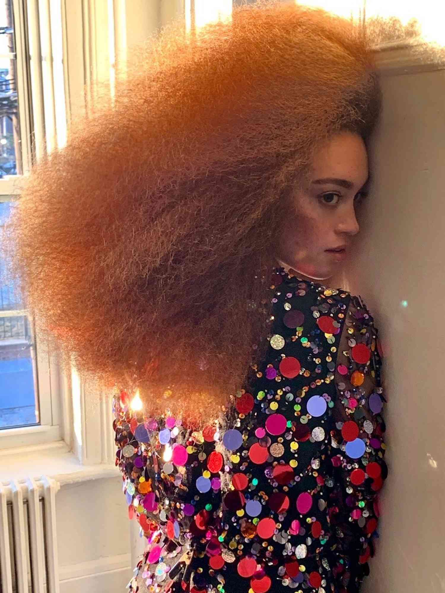Woman with brushed out ginger natural curls and sequined top