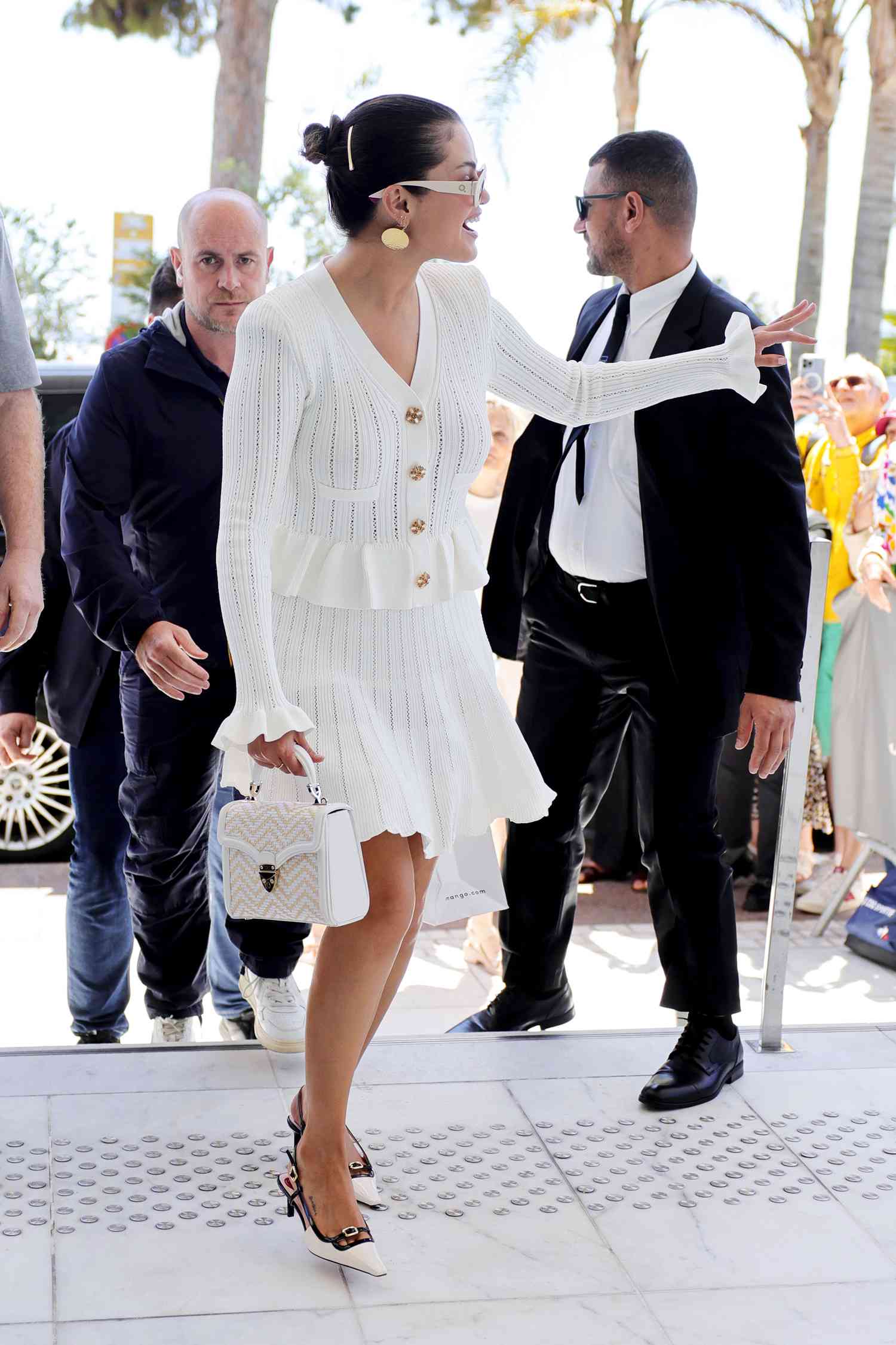 A photo of Selena Gomez wearing a white matching cardigan and skirt.