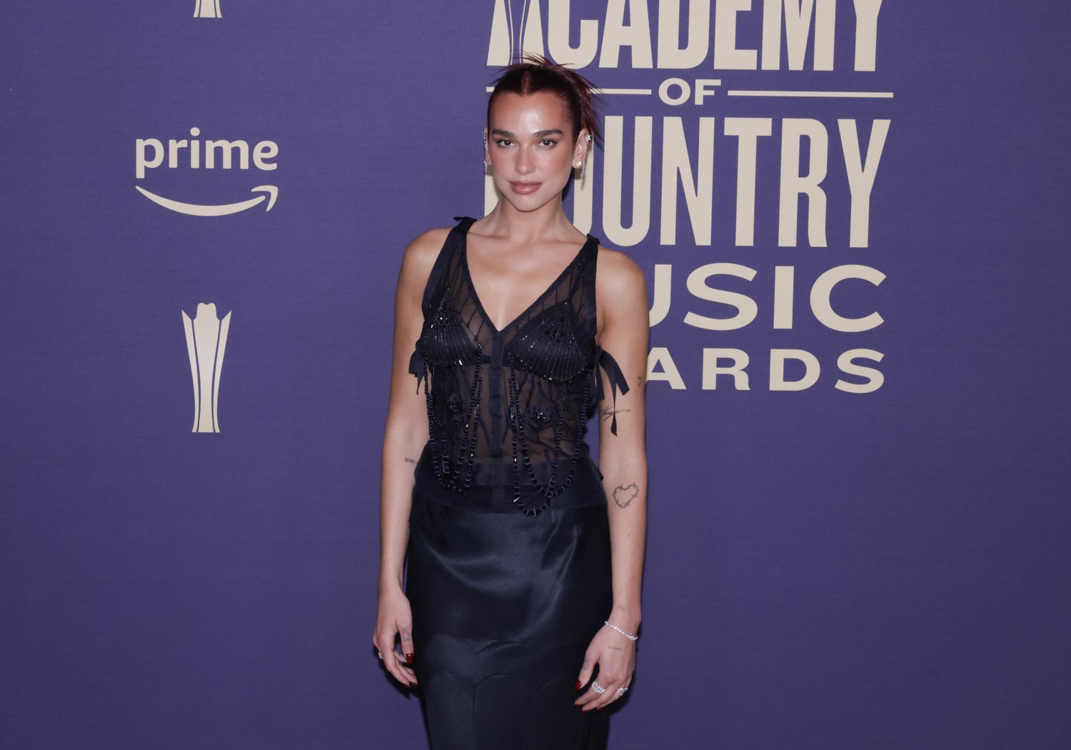 Dua Lipa wearing a blue dress on the carpet of the American Country Music Awards.