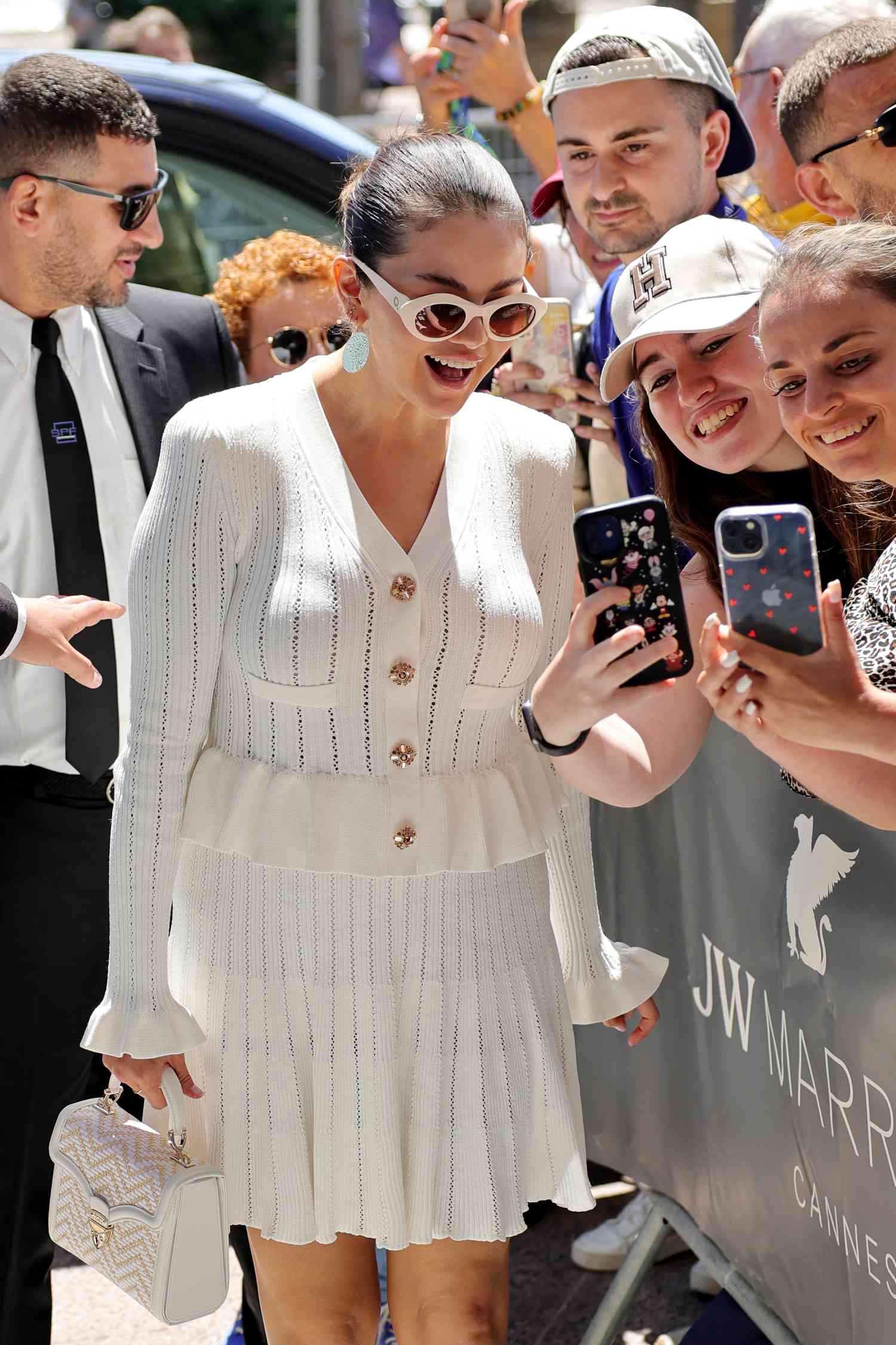 A photo of Selena Gomez wearing a white matching cardigan and skirt.