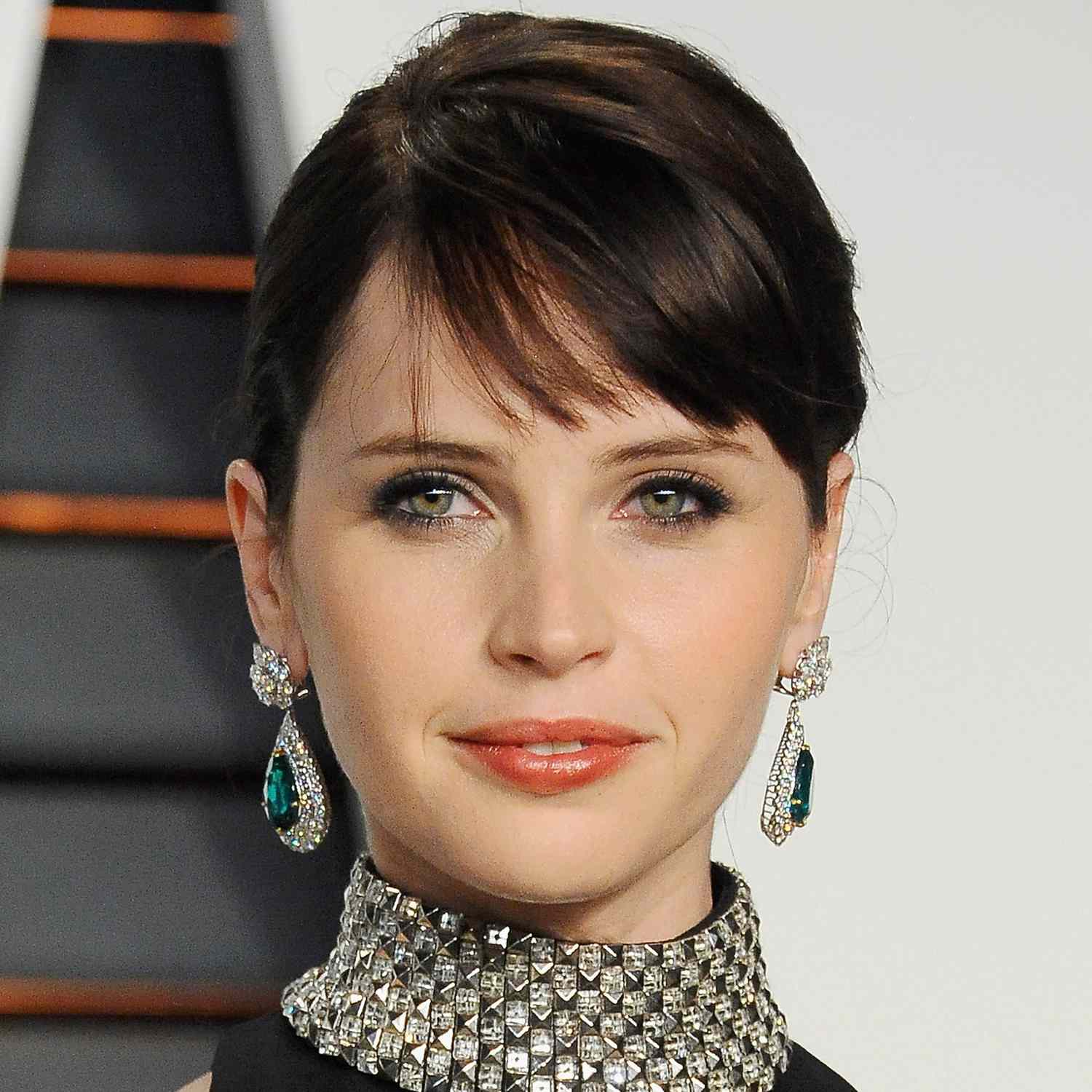 Felicity Jones wears french bangs brushed to the side for the Vanity Fair party