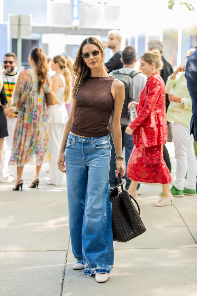 NEW YORK, NEW YORK - SEPTEMBER 10: Alessandra Ambrosio wears brown transparent top, denim jeans, bag outside PatBo during New York Fashion Week on September 10, 2024 in New York City.