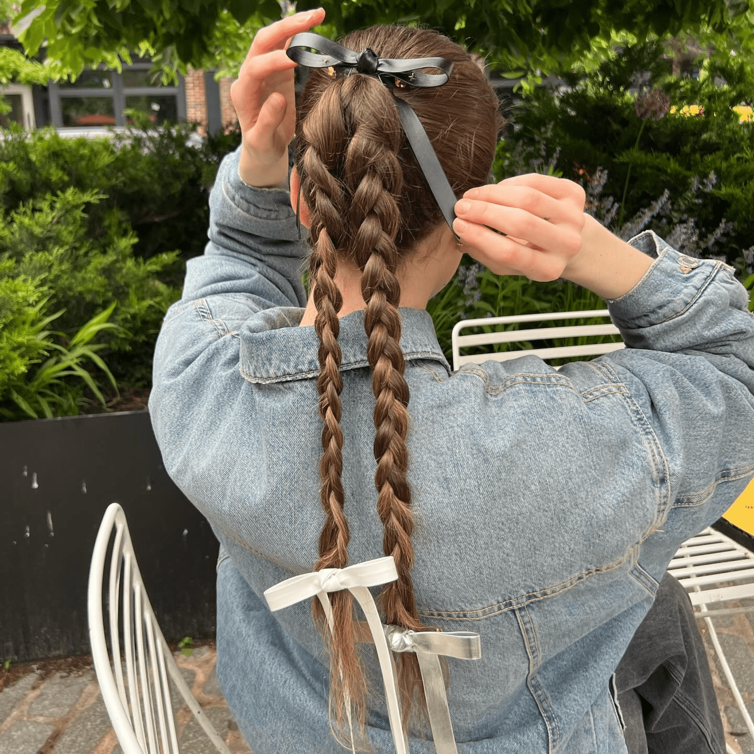 Close up of the back of a models head showing double braids and three bows. 