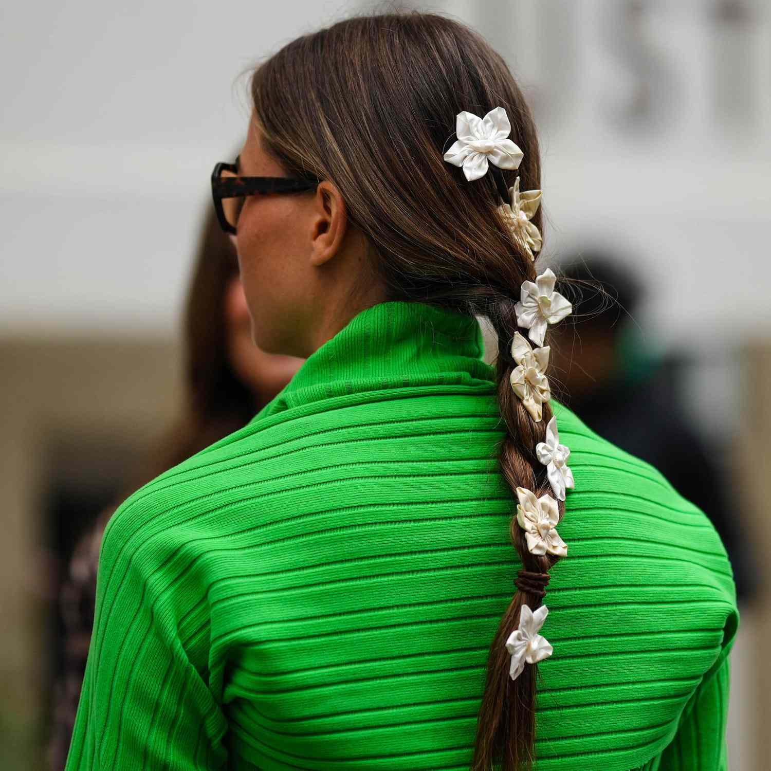 Guest in Copenhagen attends fashion week with floral accessories along the spine of her braid