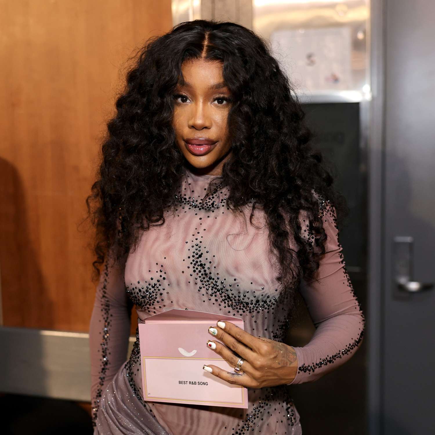 SZA with a center-parted curly hairstyle