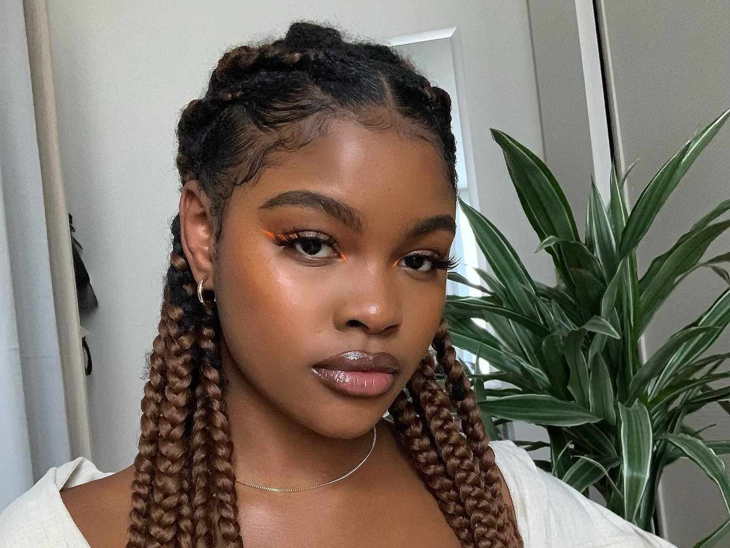 A woman with box braids pulled off her face in a half-up, half-down style