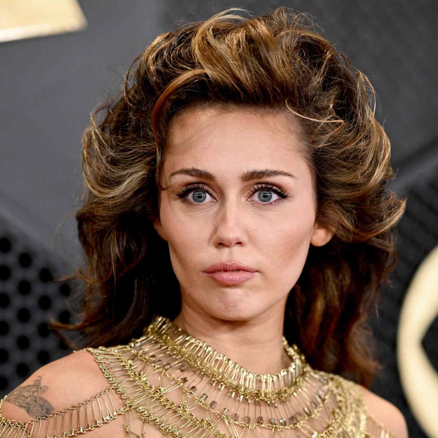 Miley Cyrus with fluffy, brushed back hair on the red carpet