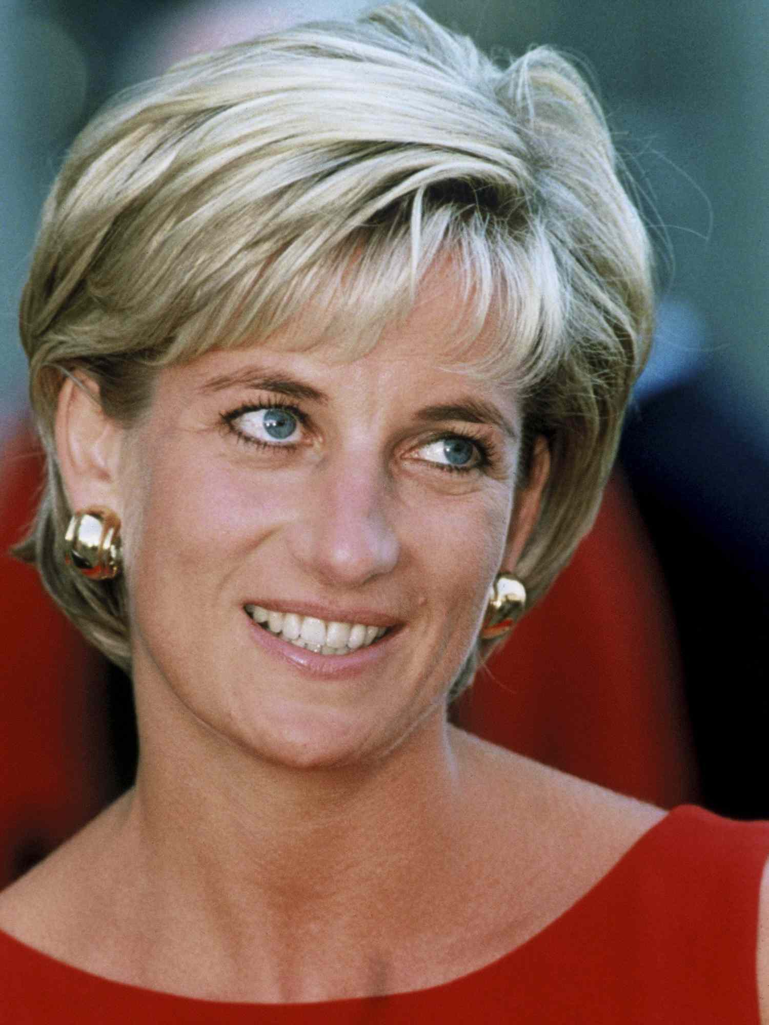 Princess Diana with a long pixie cut with highlights, gold hoop earrings, and a red dress