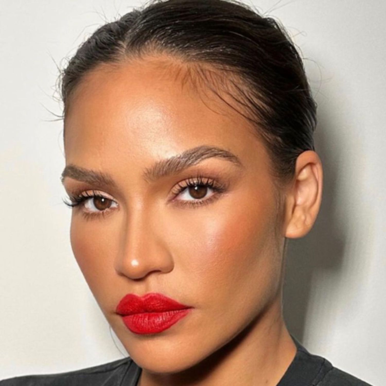 Bright red lipstick with clean, bronzed skin and lashes.