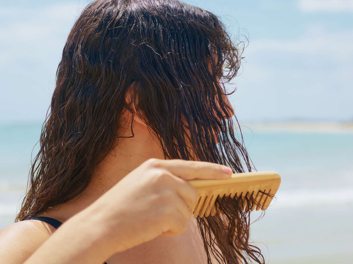 woman combing her wet curly hair at the beach