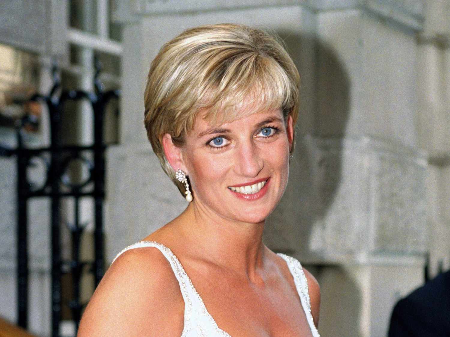 Princess Diana wears a long pixie cut with highlighted bangs and pearl drop earrings
