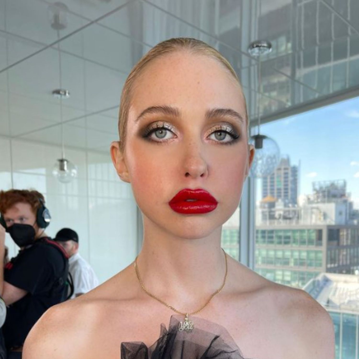 An intense, shiny red lip with a silver and black smoky eye.